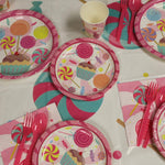 Candy Dinner Plates, cups, hot pink fork and spoons on the table.